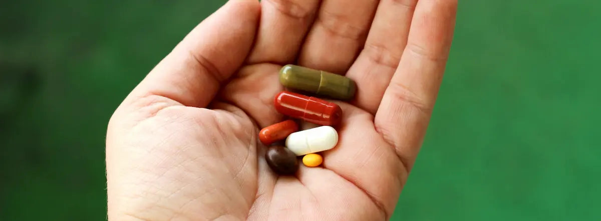 Older New Zealander comparing a multivitamin capsule and tablet at home