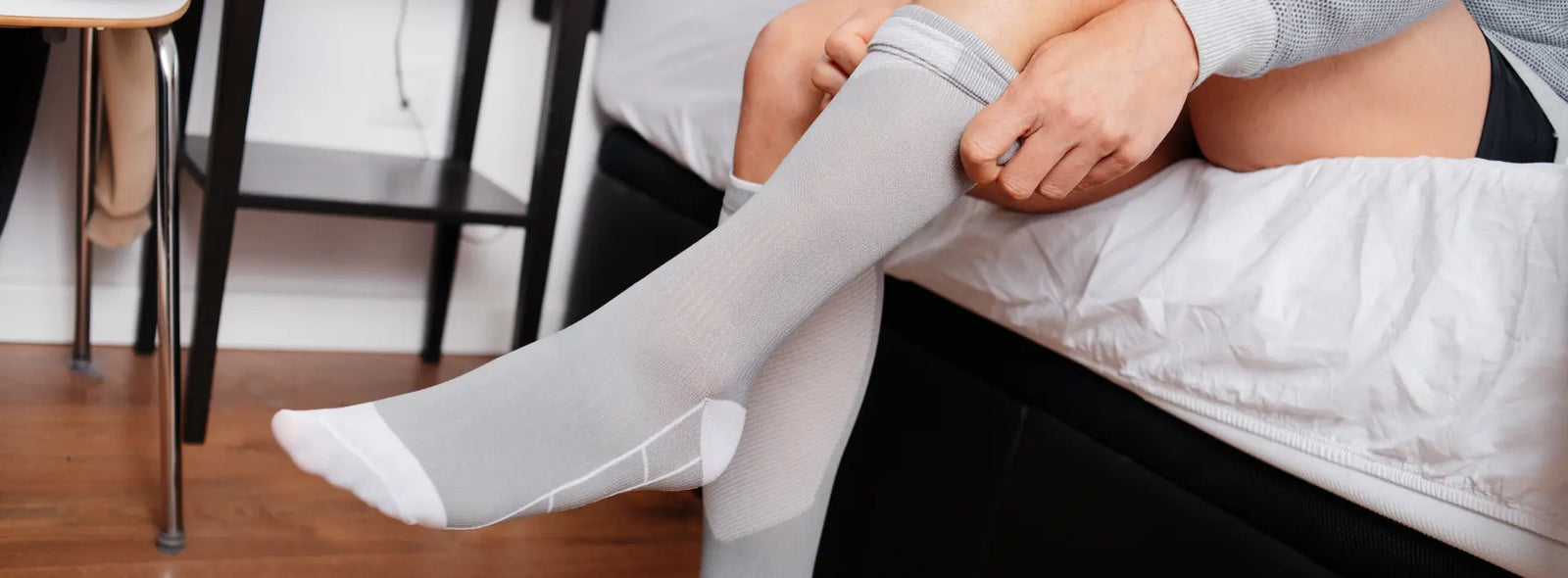 Older New Zealand adult and caregiver arranging a compression stocking, movement reminder and vein support supplement as separate routine steps