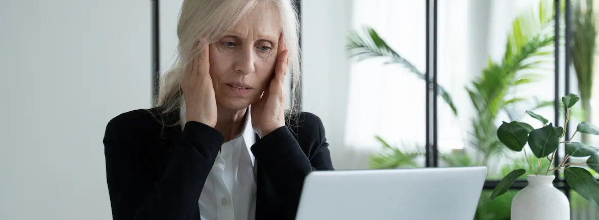 New Zealand adult over 50 adjusting reading glasses while using a laptop at home