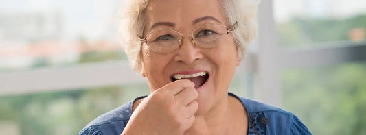 New Zealand senior reading a small label in bright light while considering eye vitamins for healthy ageing.