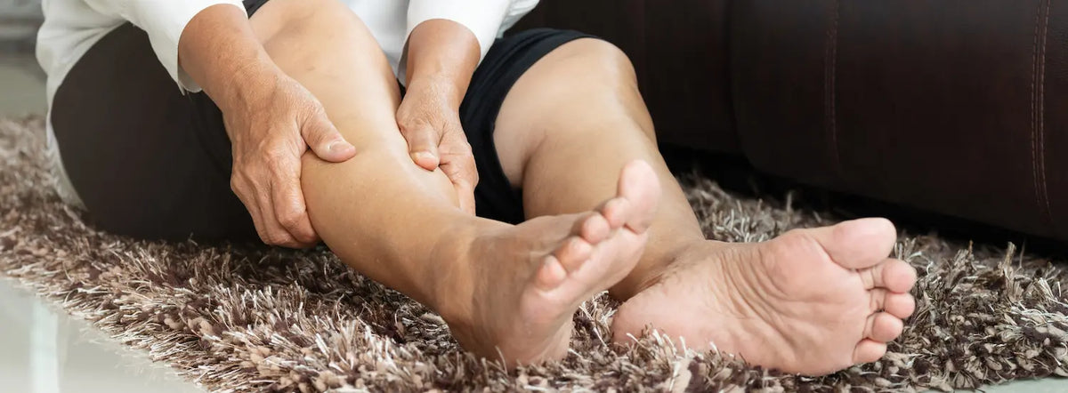 Older Kiwi gently stretching a calf at home after leg cramps after 60