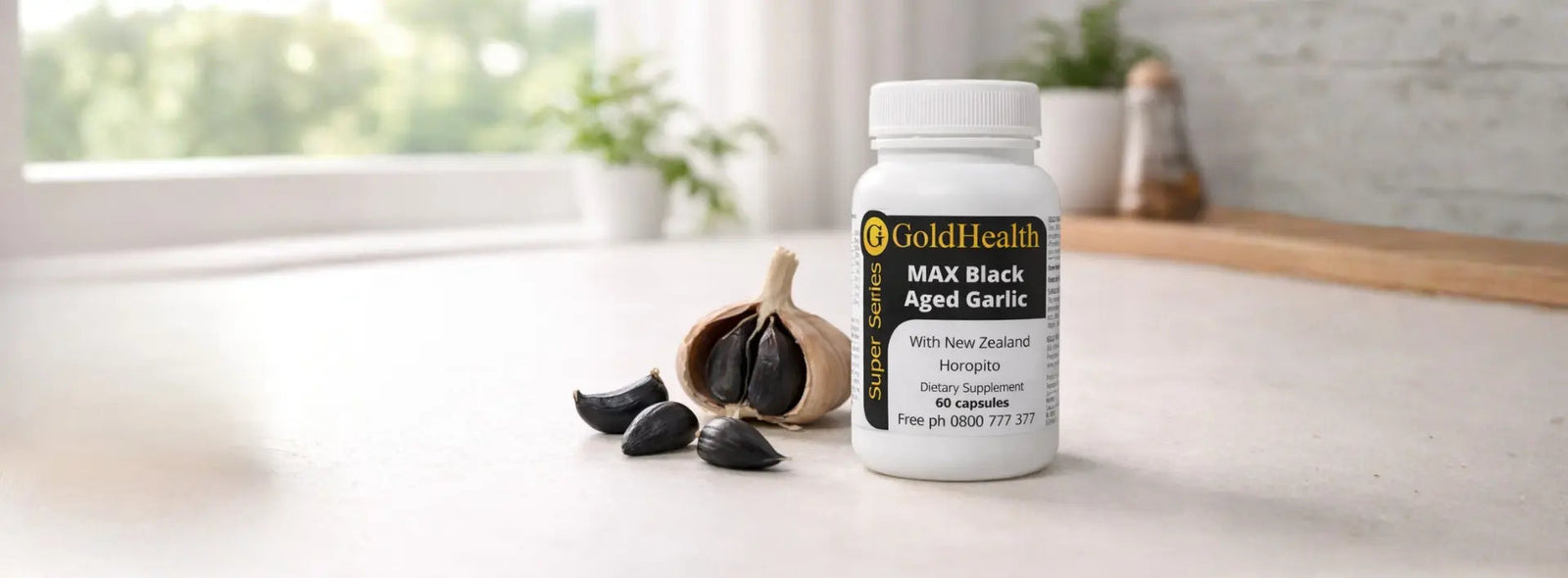Aged black garlic cloves beside a simple supplement bottle on a kitchen bench