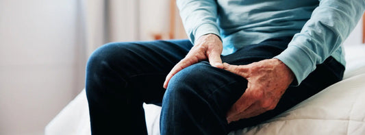 Person stretching calf to relieve a leg cramp with a glass of water nearby