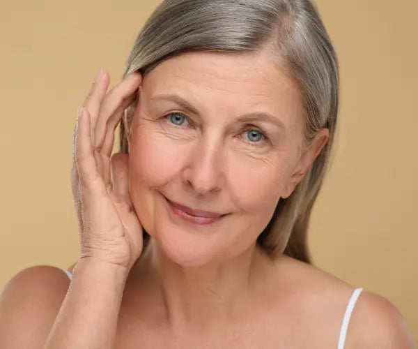 Mature woman caring for her skin, representing Gold Health skin hair and nails support